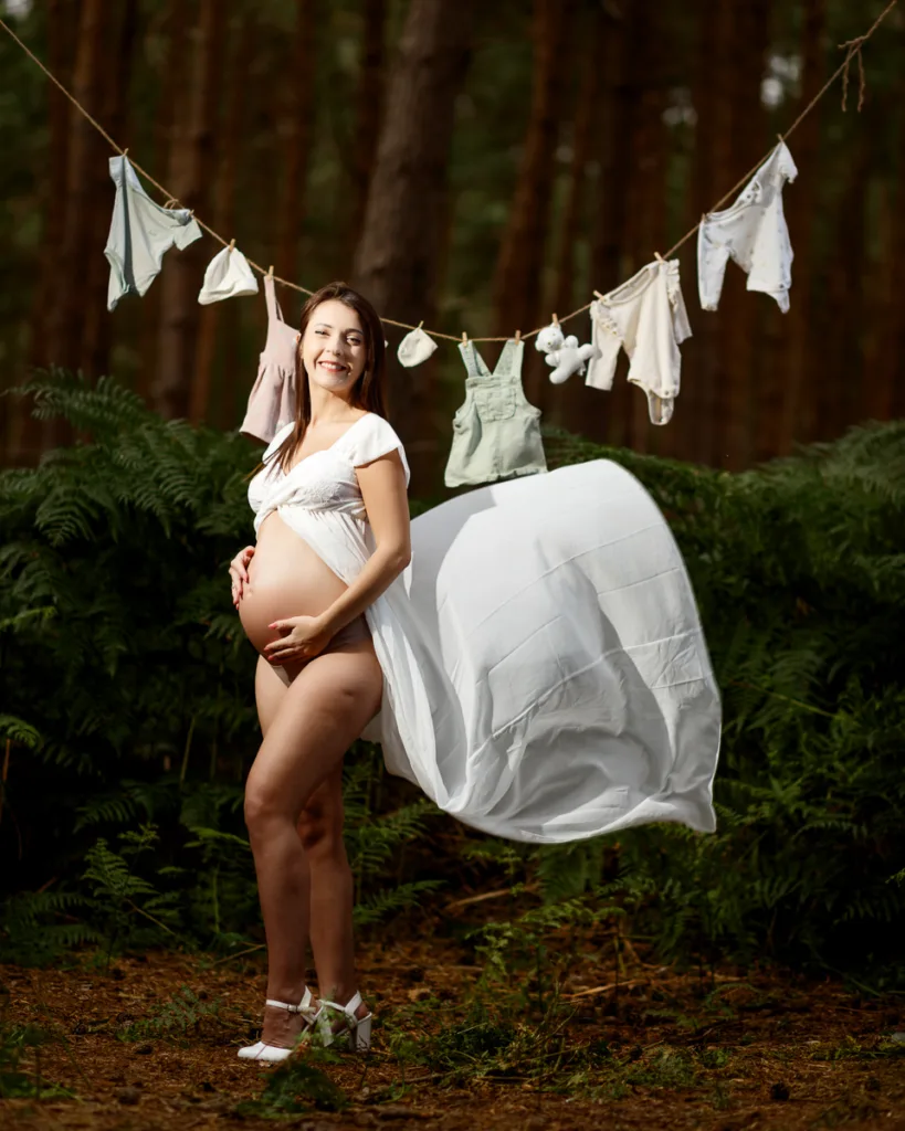 Pregnant woman outdoors with baby clothes on line.