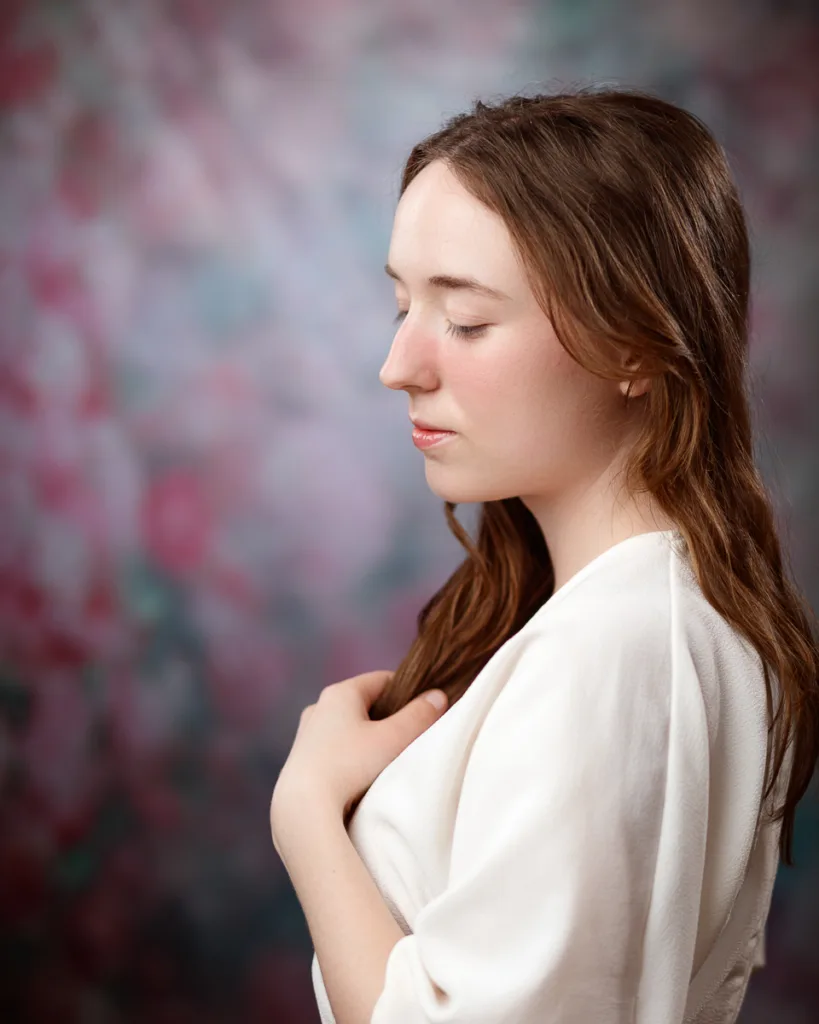 Peaceful person in white with blurred floral background.