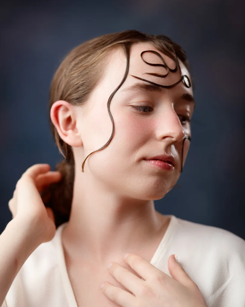 Person with artistic hair design on face, side pose.