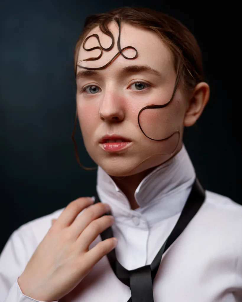 Person with styled hair and black tie on shirt.