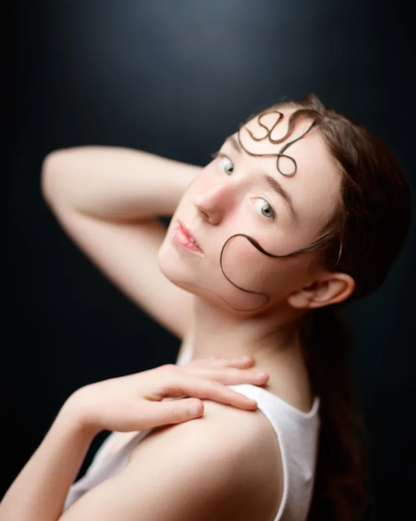 Artistic portrait with abstract face lines, dark background.