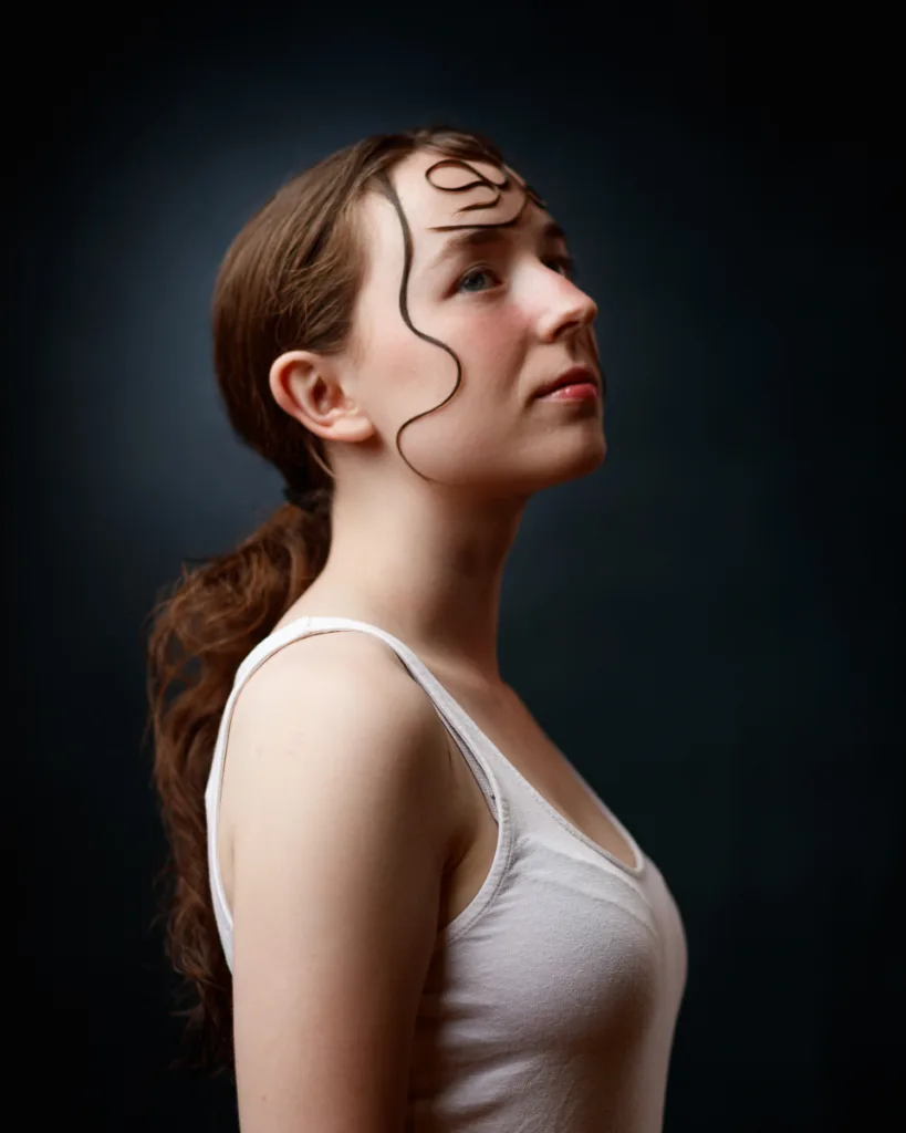 Woman with loose hair strands gazes upwards.