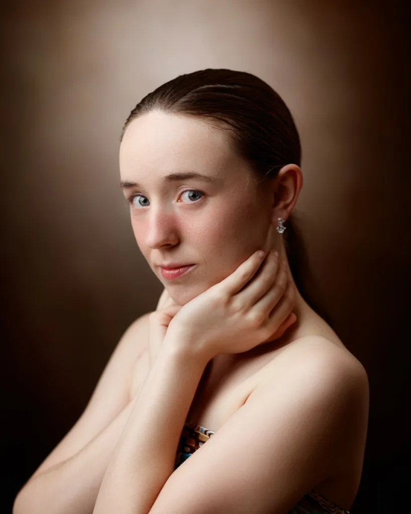 Woman posing thoughtfully against a brown background.