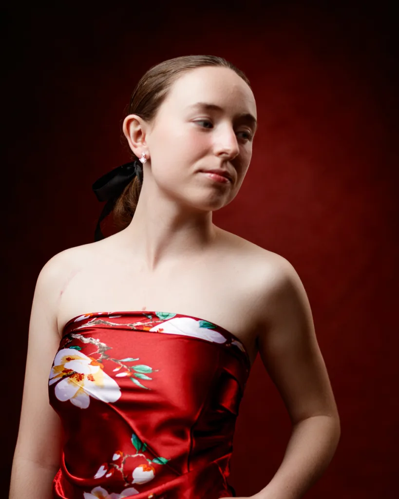 Woman in floral strapless dress against red backdrop.