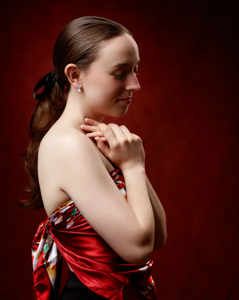 Woman in red scarf with closed eyes and clasped hands.