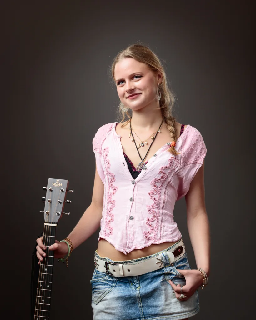 Person posing with guitar in casual outfit.