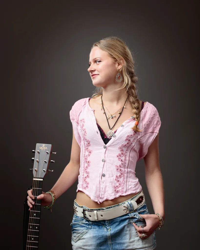 Woman holding guitar with braided hair.