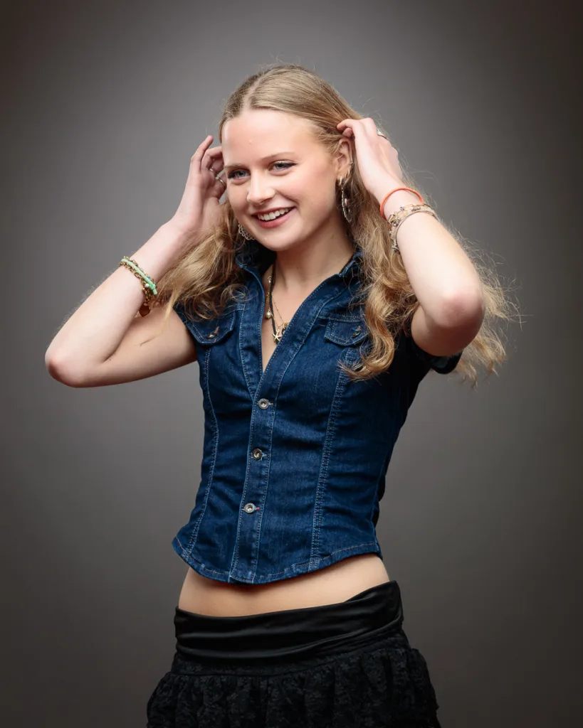 Woman smiling, wearing denim shirt.