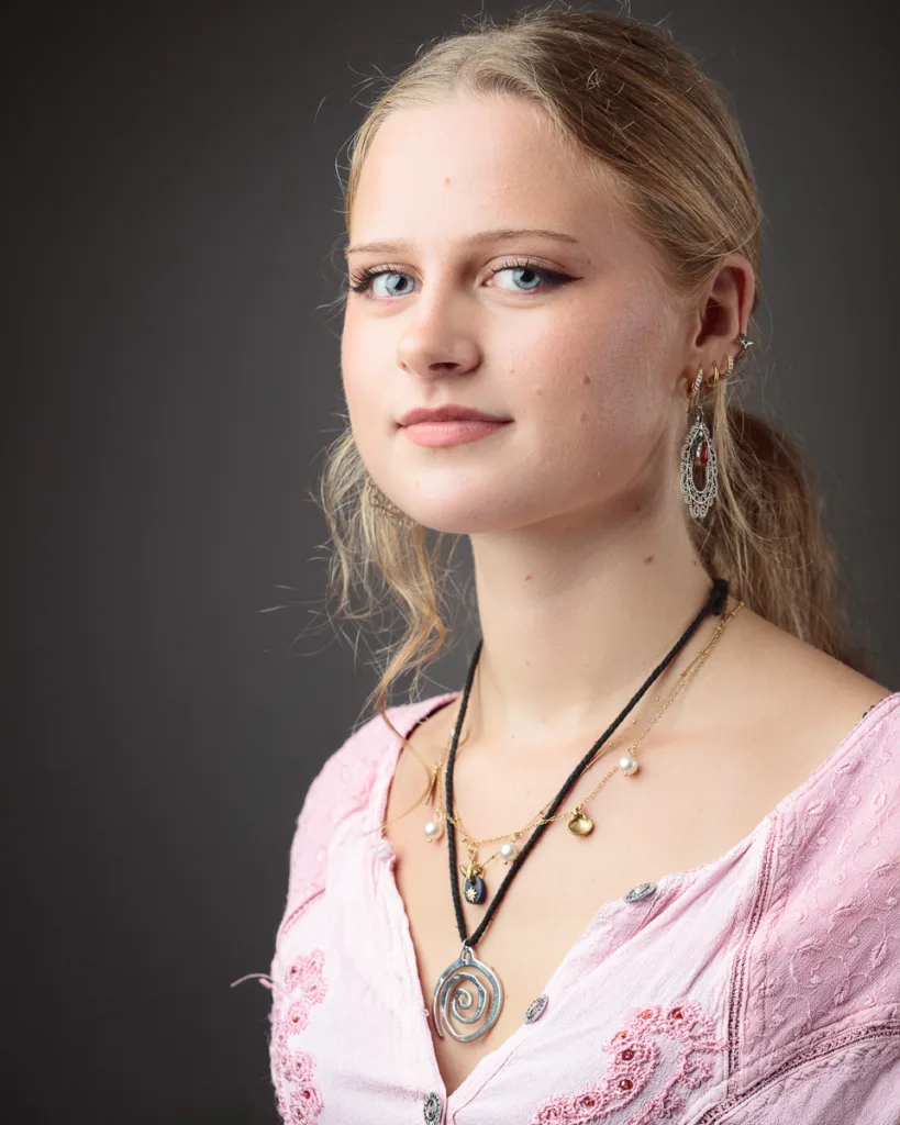Woman wearing pink top with jewellery.