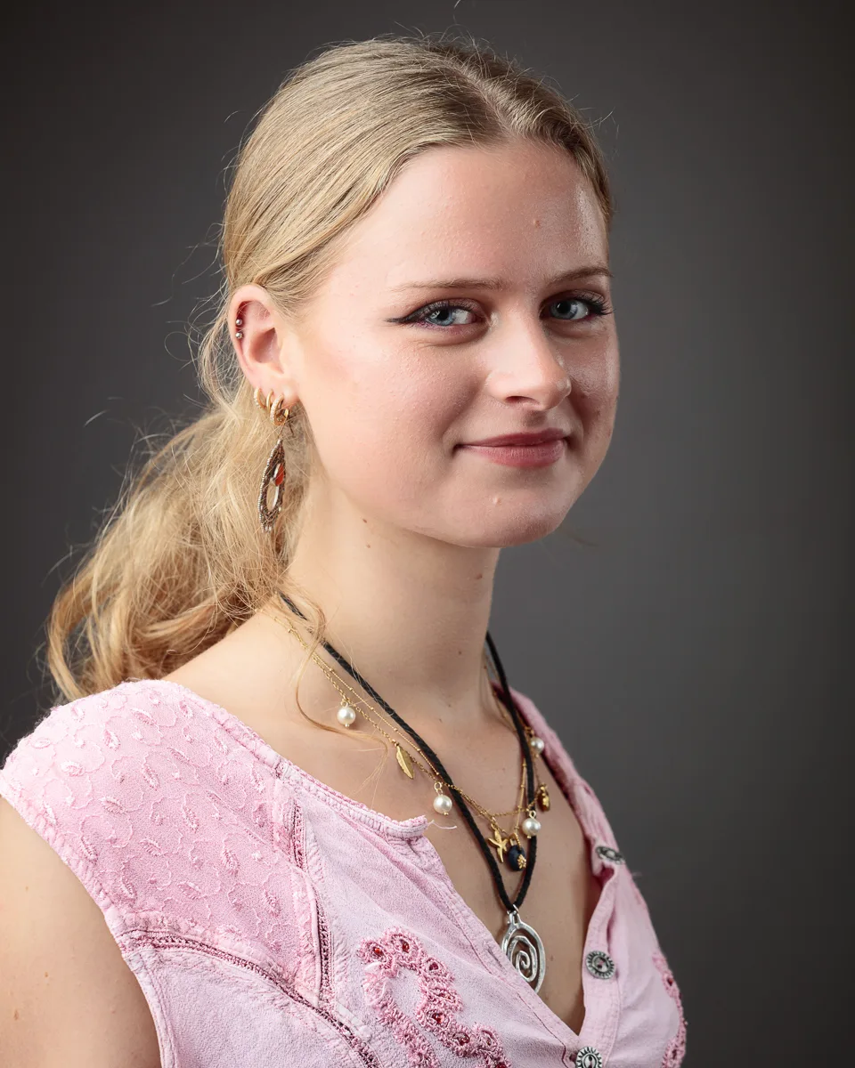 Woman with blonde hair and pink blouse smiling.