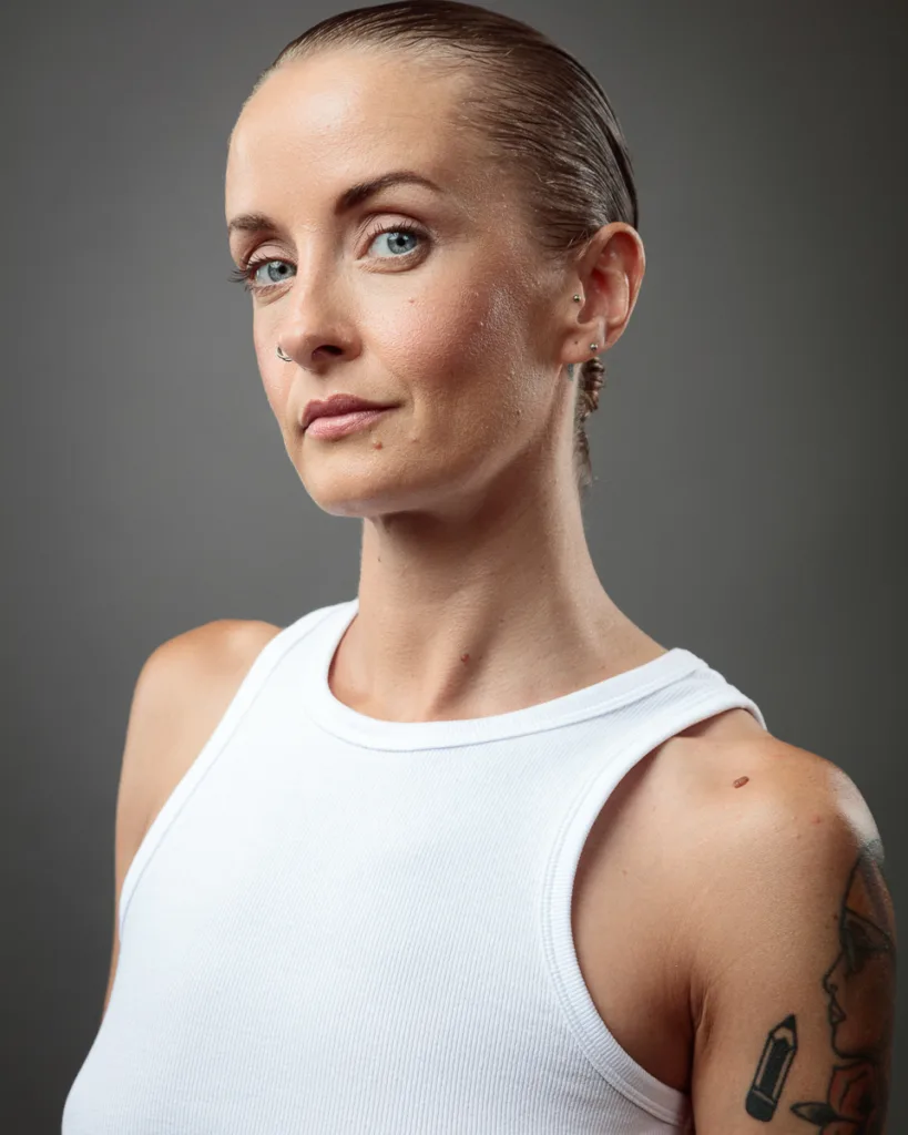 Person in white tank top with tattoos.