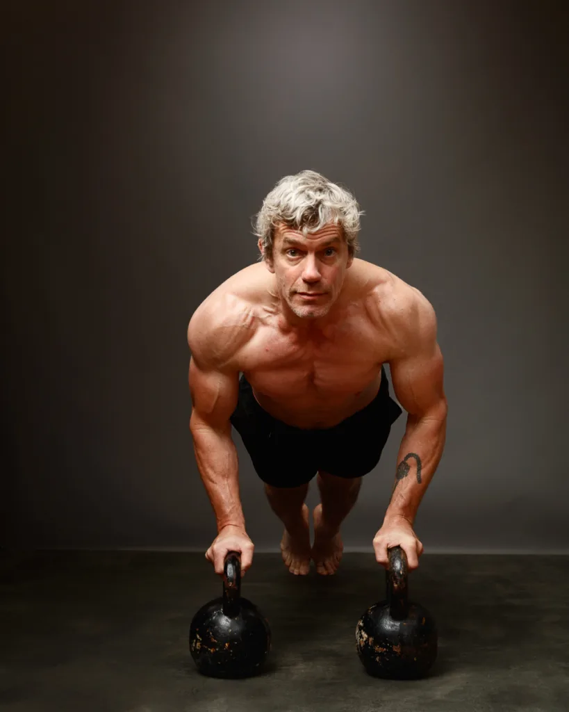 Man performing push-up on kettlebells.