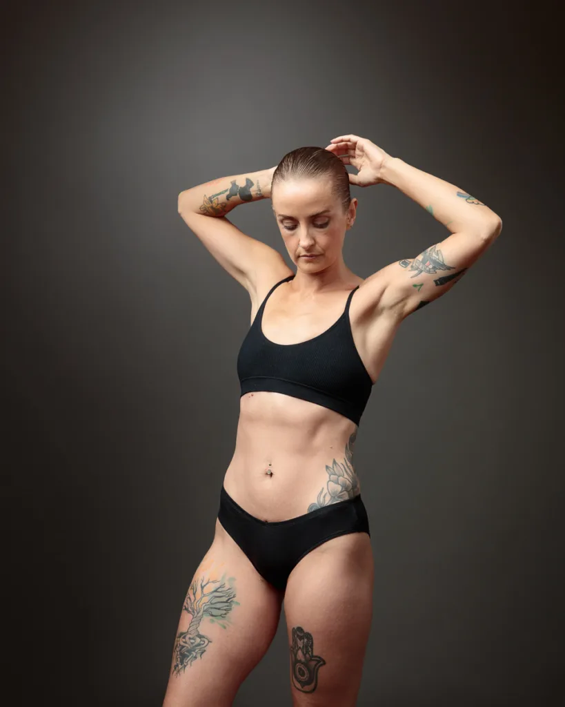 Person with tattoos posing in black sportswear.