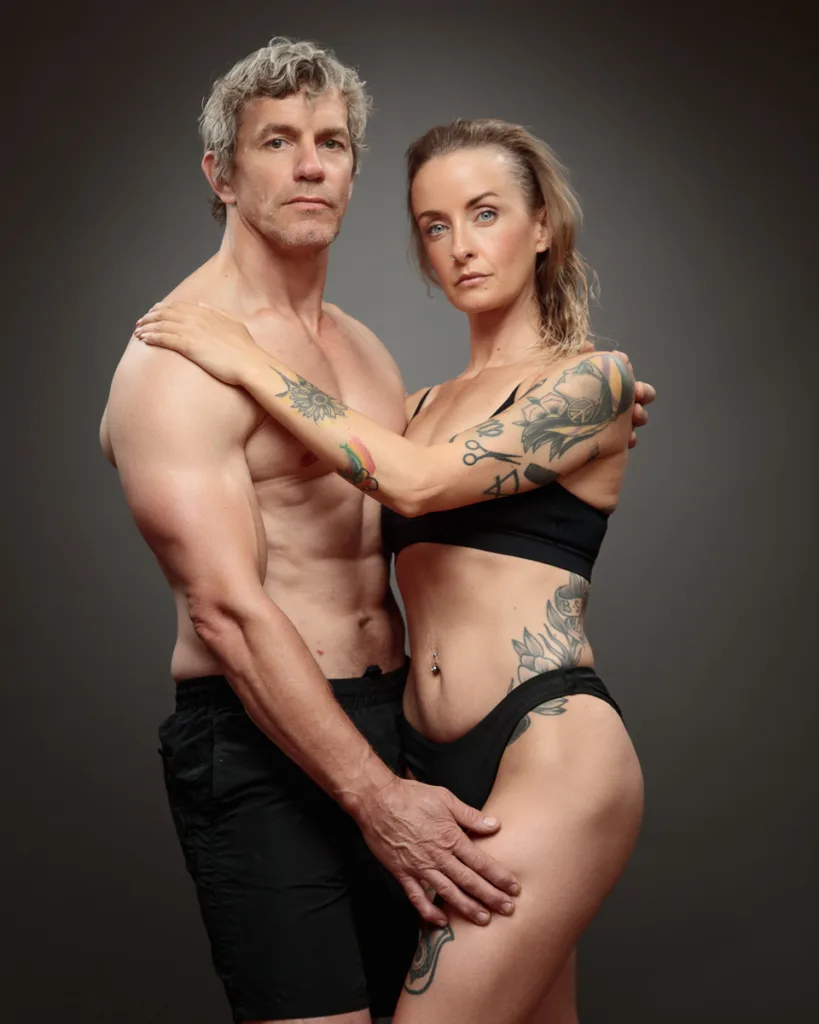Fit couple with tattoos posing confidently together.