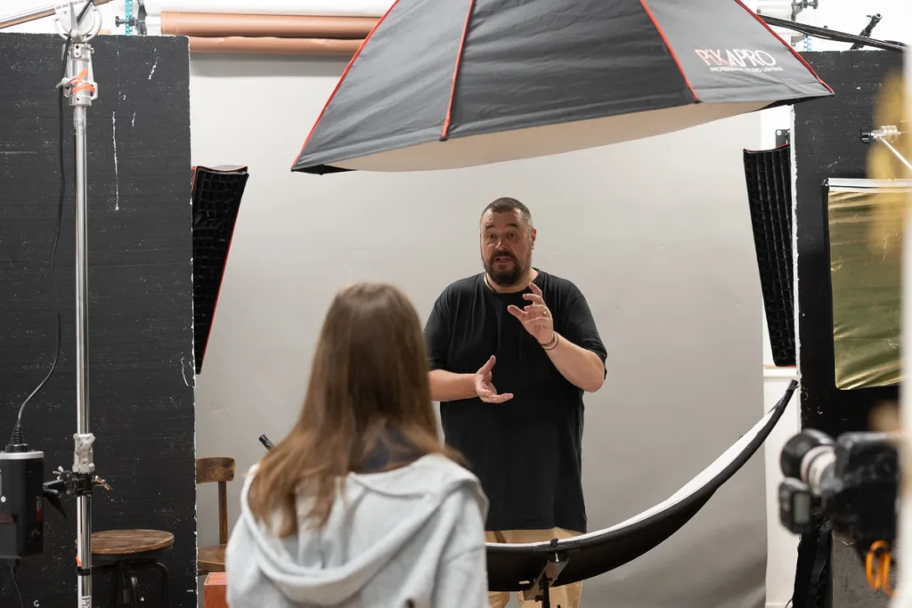 Photographer instructs model in studio lighting setup.