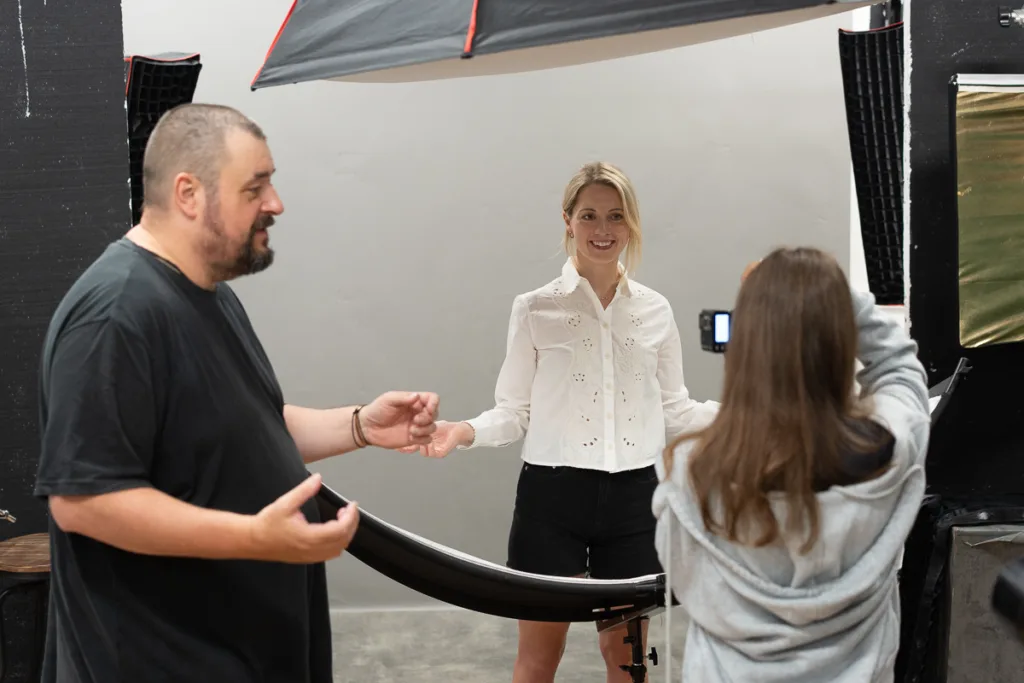 Photographer directing studio photo shoot of model.