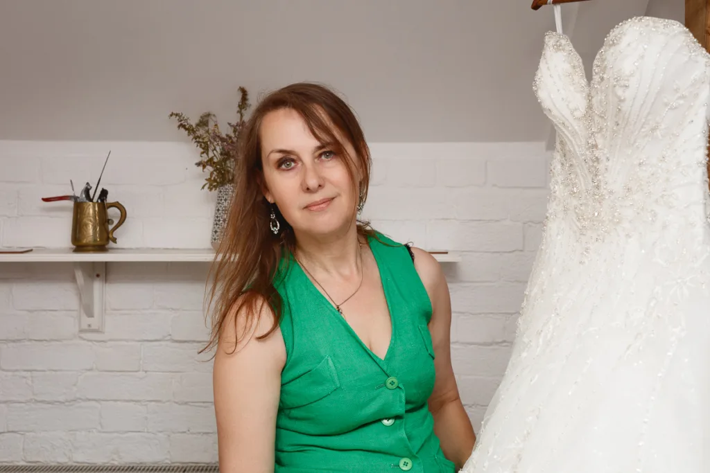 Woman in green dress beside white wedding gown.