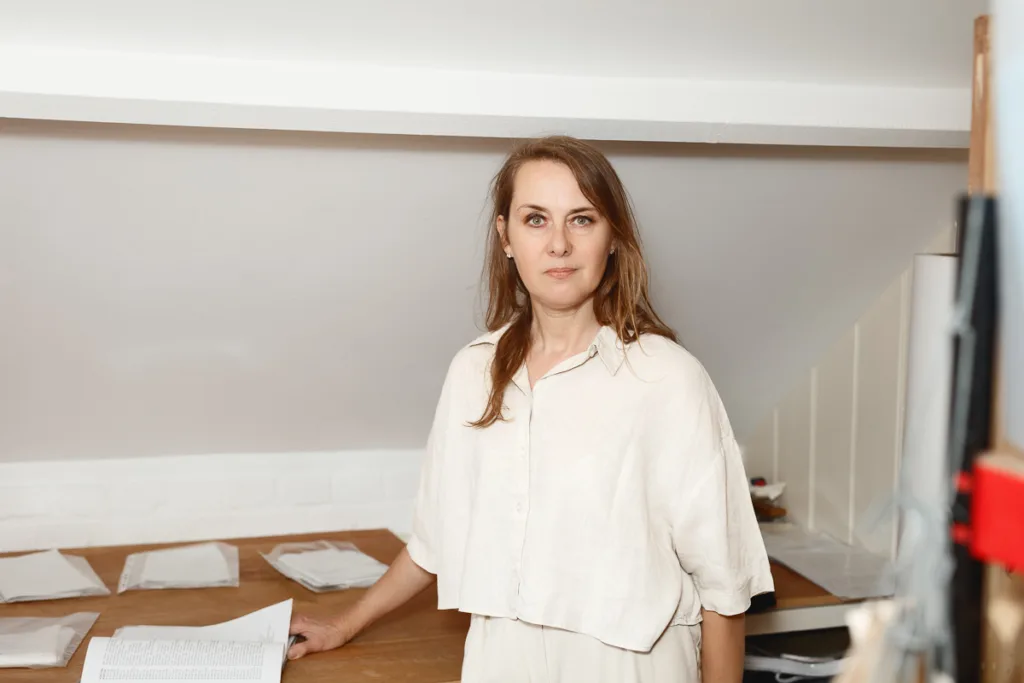 Woman standing by desk with papers.