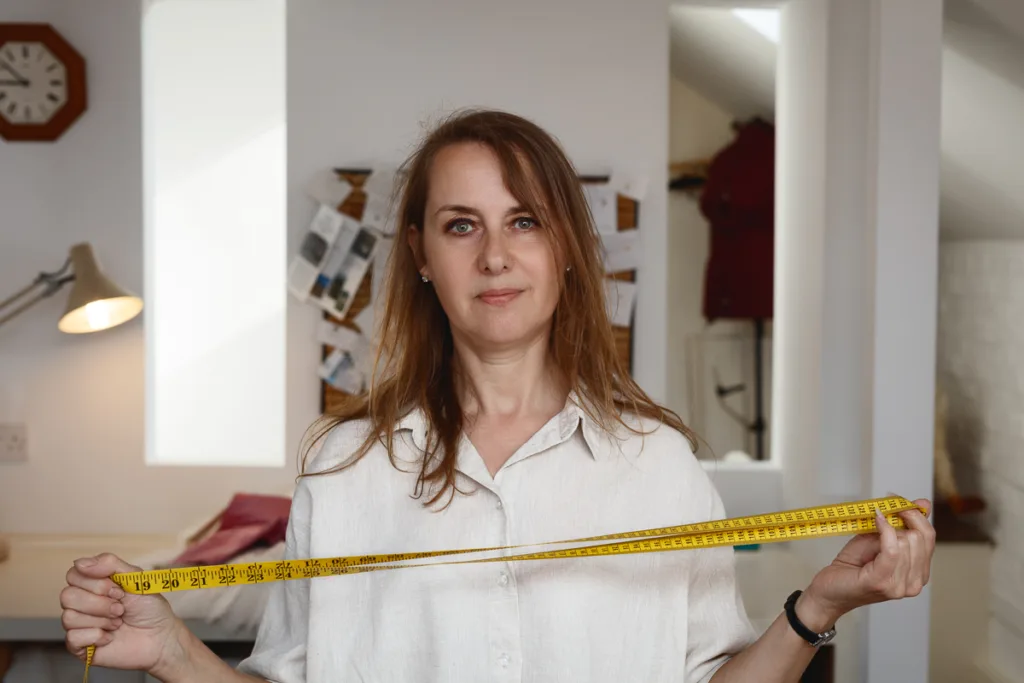 Woman holding tape measure in a room.