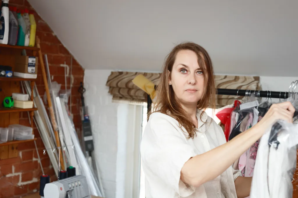 Woman organising clothes in a sewing room.