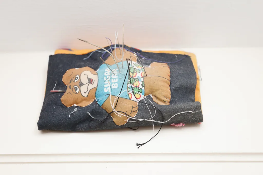 Stuffed fabric toy bear with loose threads.