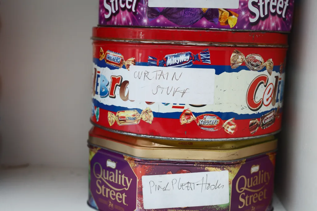 Stacked tin containers with hand-written labels.