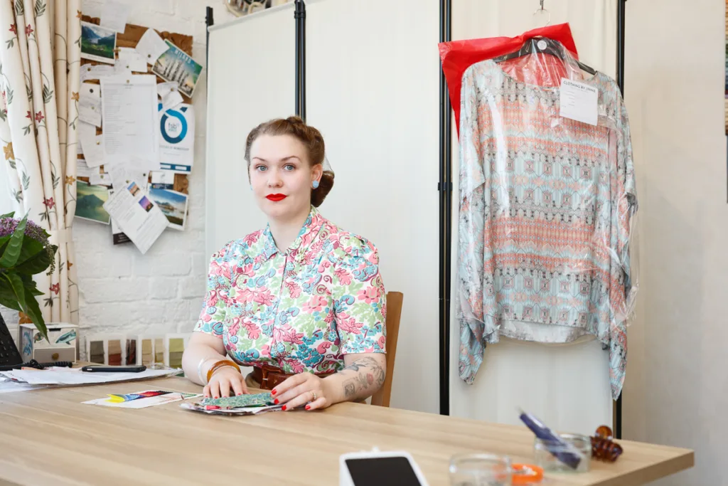 Woman with fabric samples at a desk.