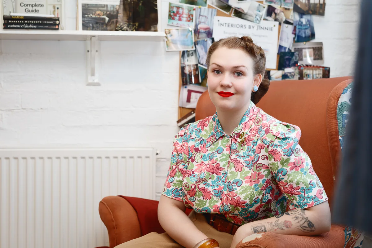 Woman in floral blouse sitting in vintage interior.