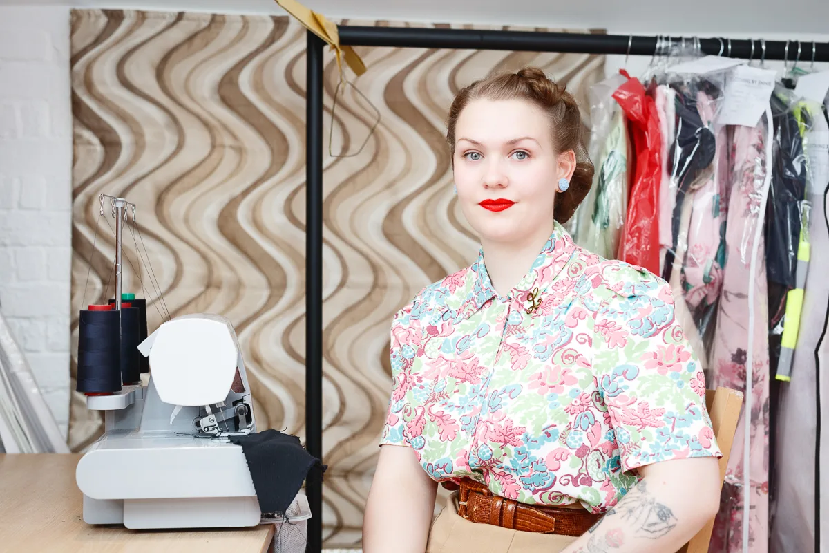 Woman in floral shirt with sewing machine.