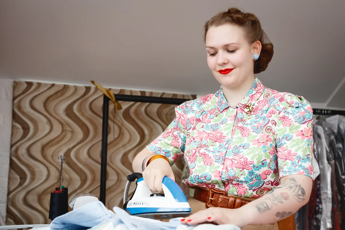 Woman ironing clothes in colourful blouse.