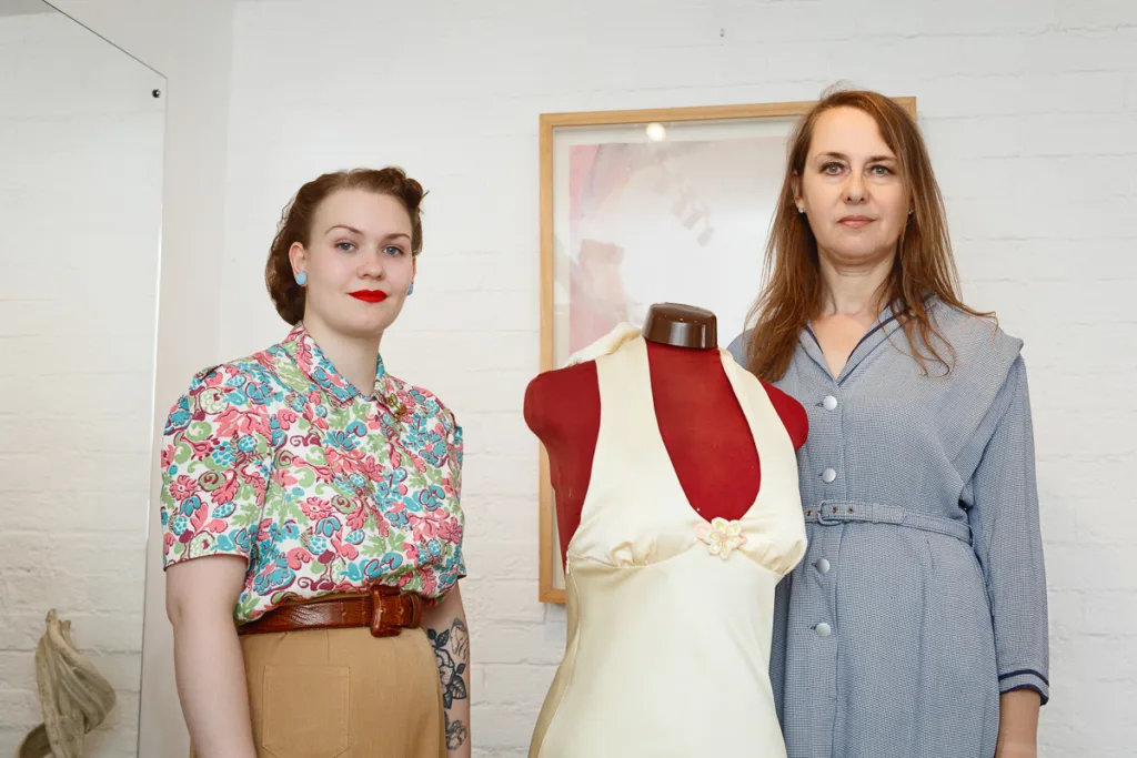 Two women with vintage fashion mannequin on display.