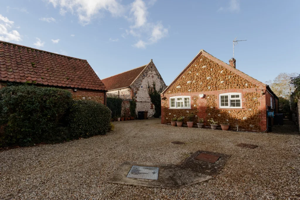 Traditional brick cottage with gravel driveway.