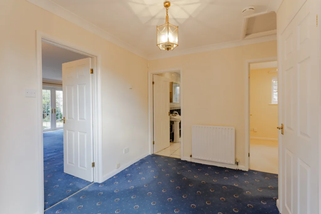 Empty hallway with carpet and open doors.