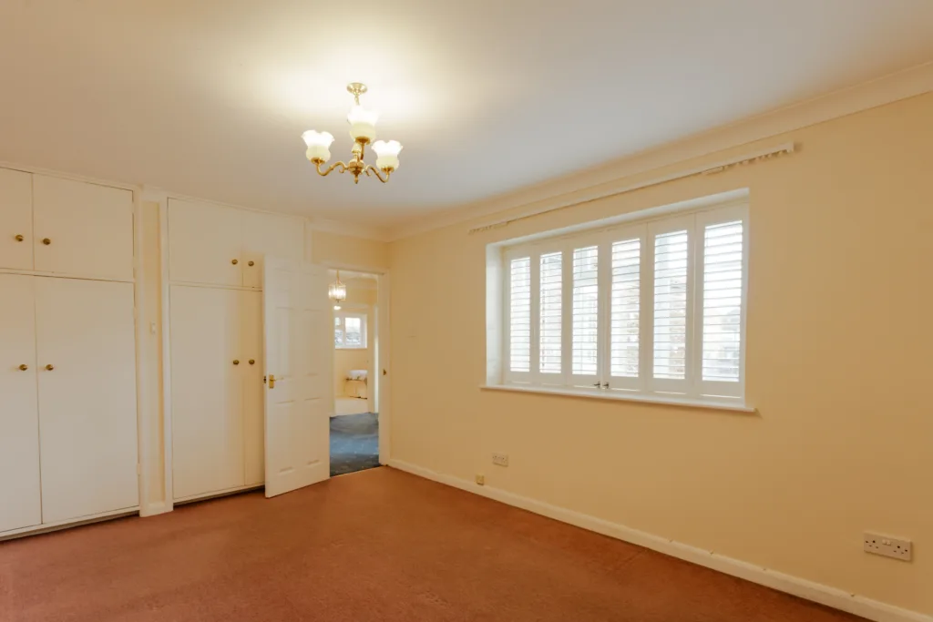 Empty room with carpet and window shutters.