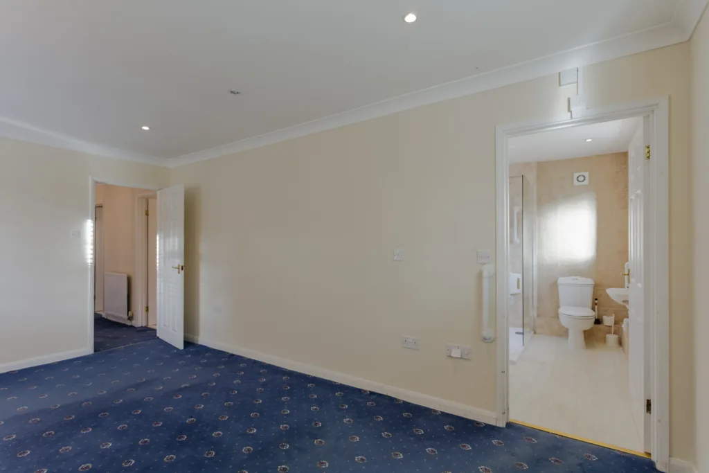 Empty room with blue carpet and bathroom door.