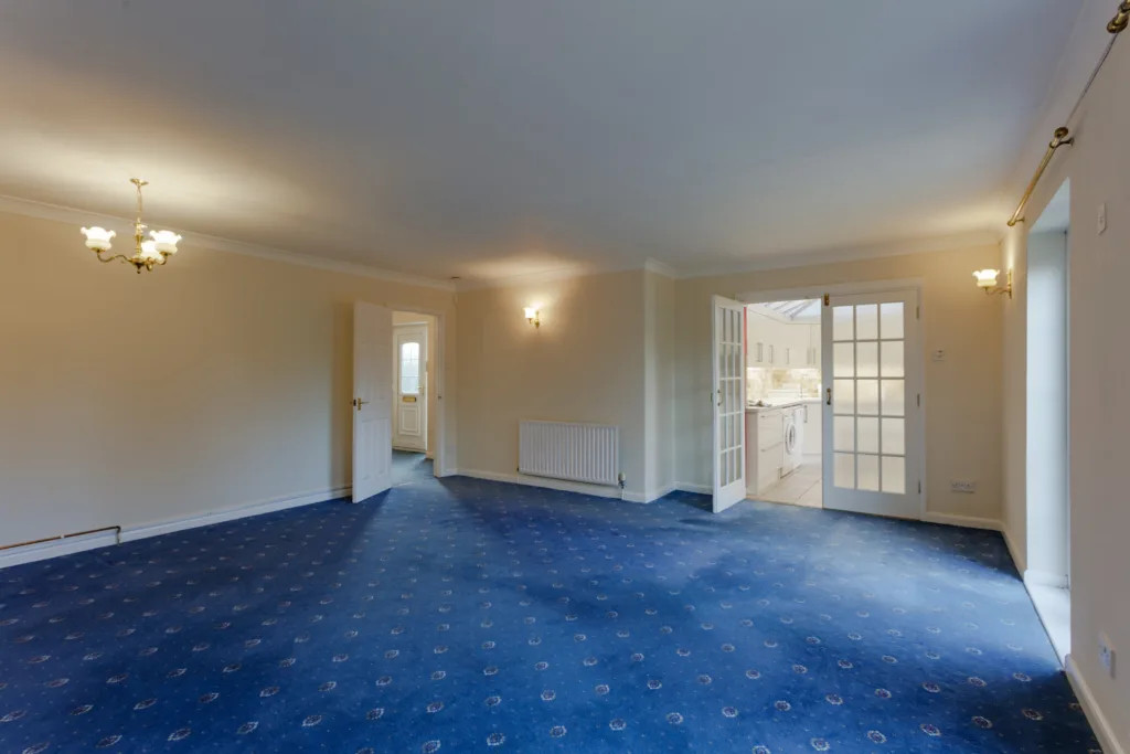 Spacious room with blue carpet and chandelier.