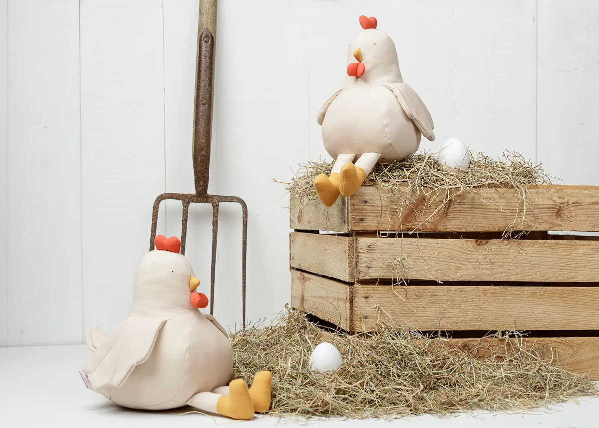 Stuffed chickens with eggs on hay bale display.