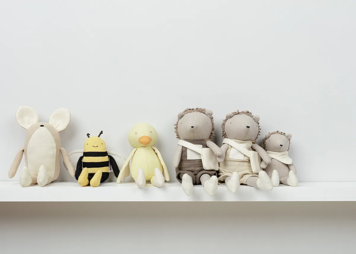 Plush toys on white shelf, five cute animals.