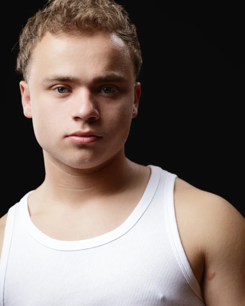 Person in white vest against black background