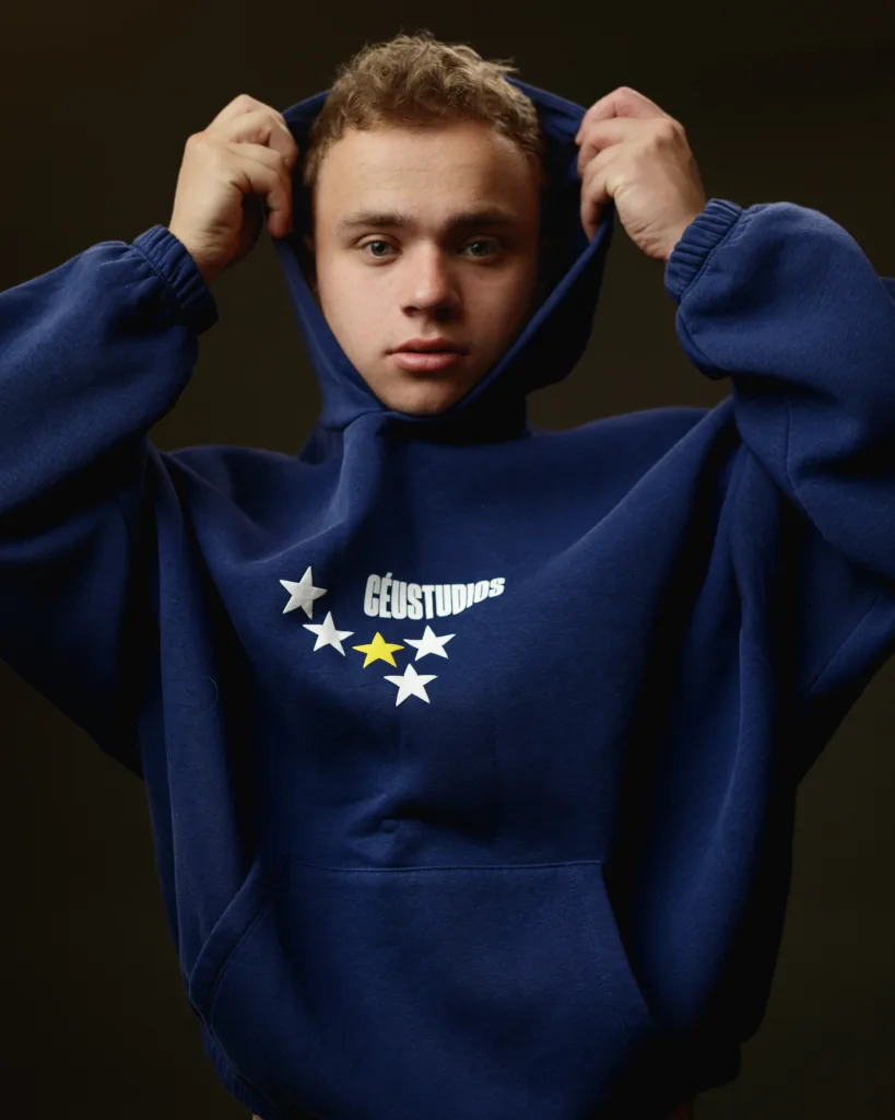 Person in blue hoodie with star design, adjusting hood.