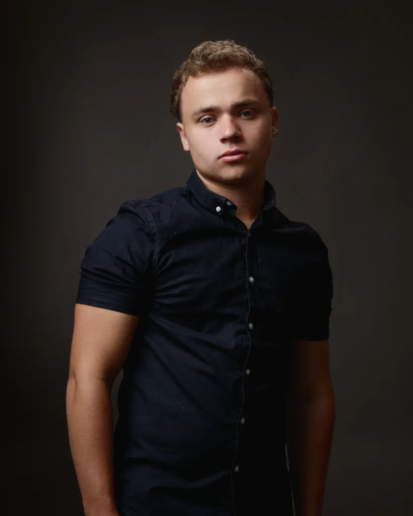 Person in dark shirt posing against dark background.