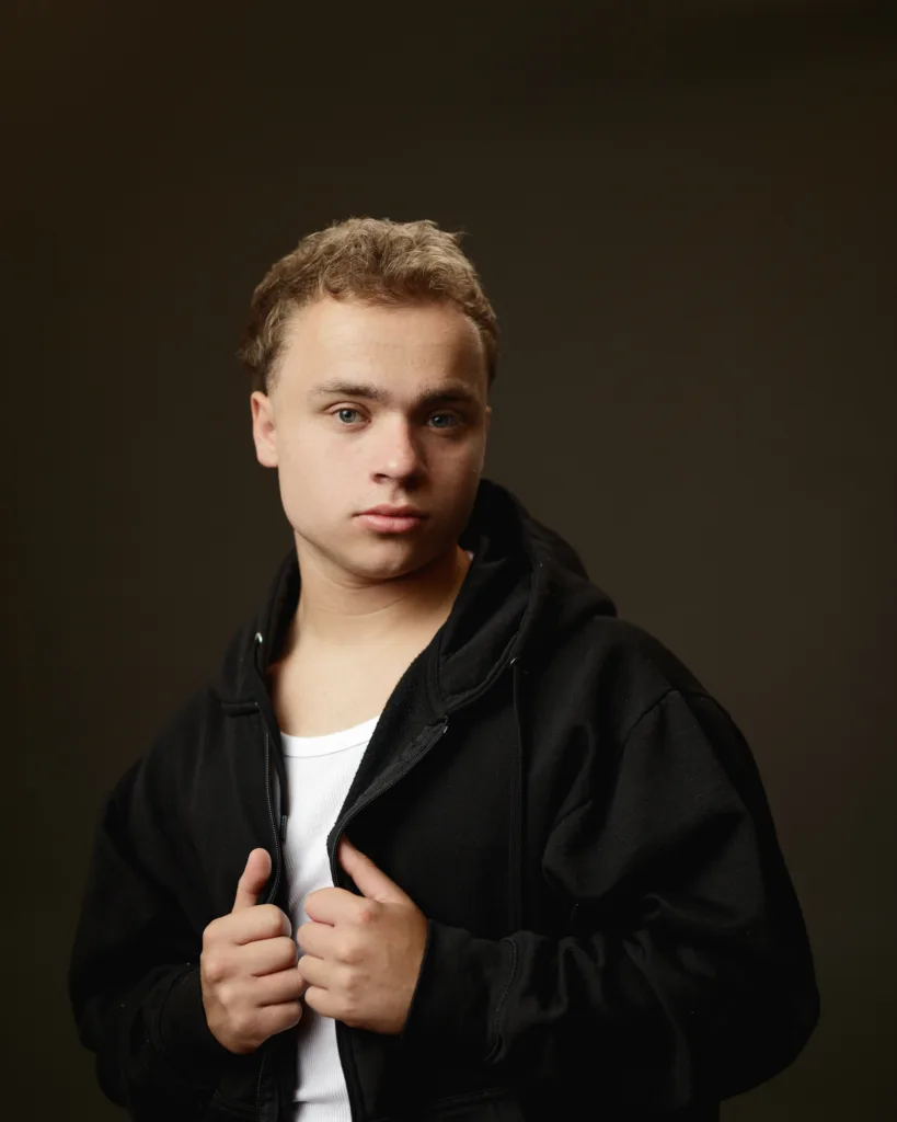 Person in black hoodie, studio portrait.