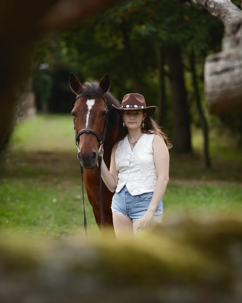 Person with horse in forest, wearing cowboy hat.