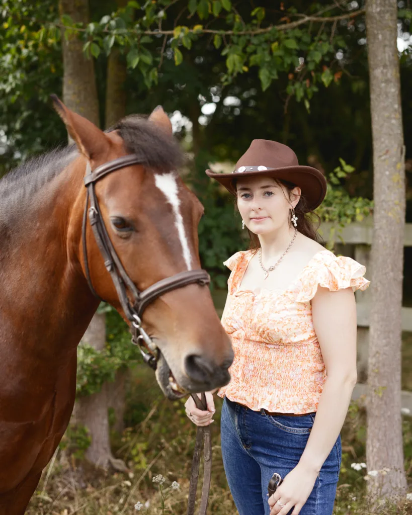 Woman in cowboy hat with a horse outdoors.