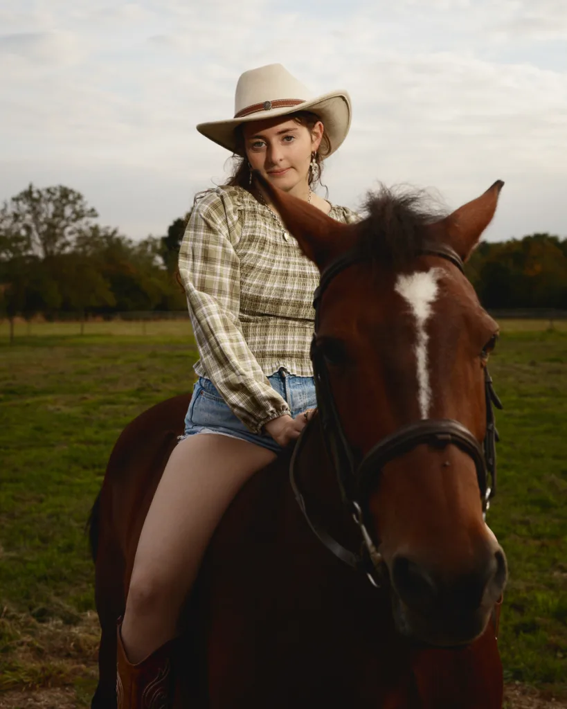 Person in cowboy hat riding a horse in field.