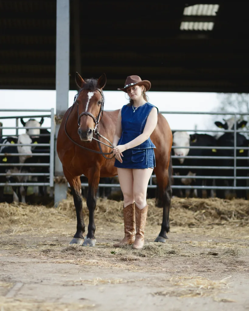 Person in cowboy hat with horse on farm.