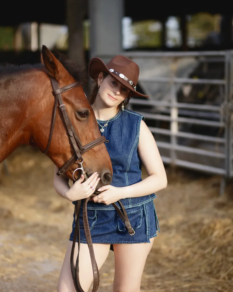 Person in denim with horse in stable setting.
