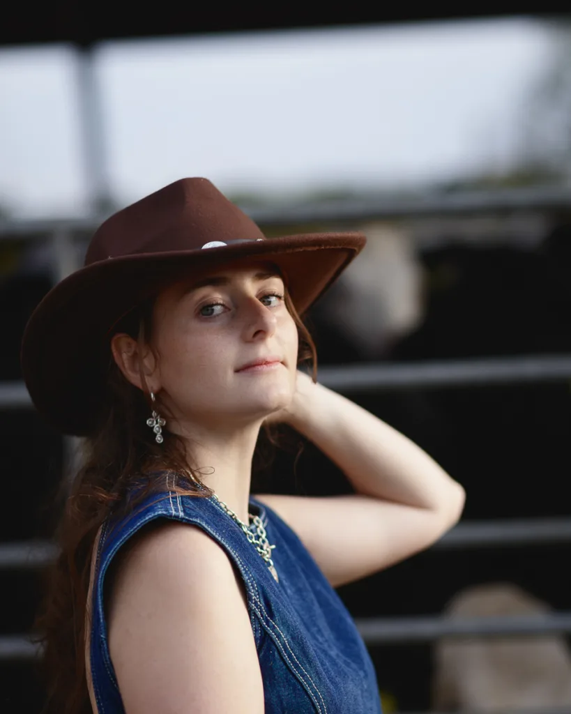 Woman in cowboy hat outdoors, hand on neck