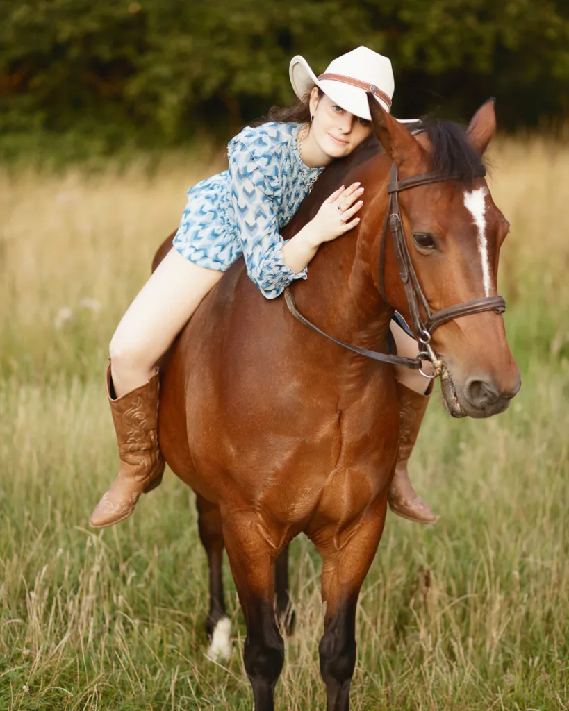 Person wearing hat riding a horse in field.