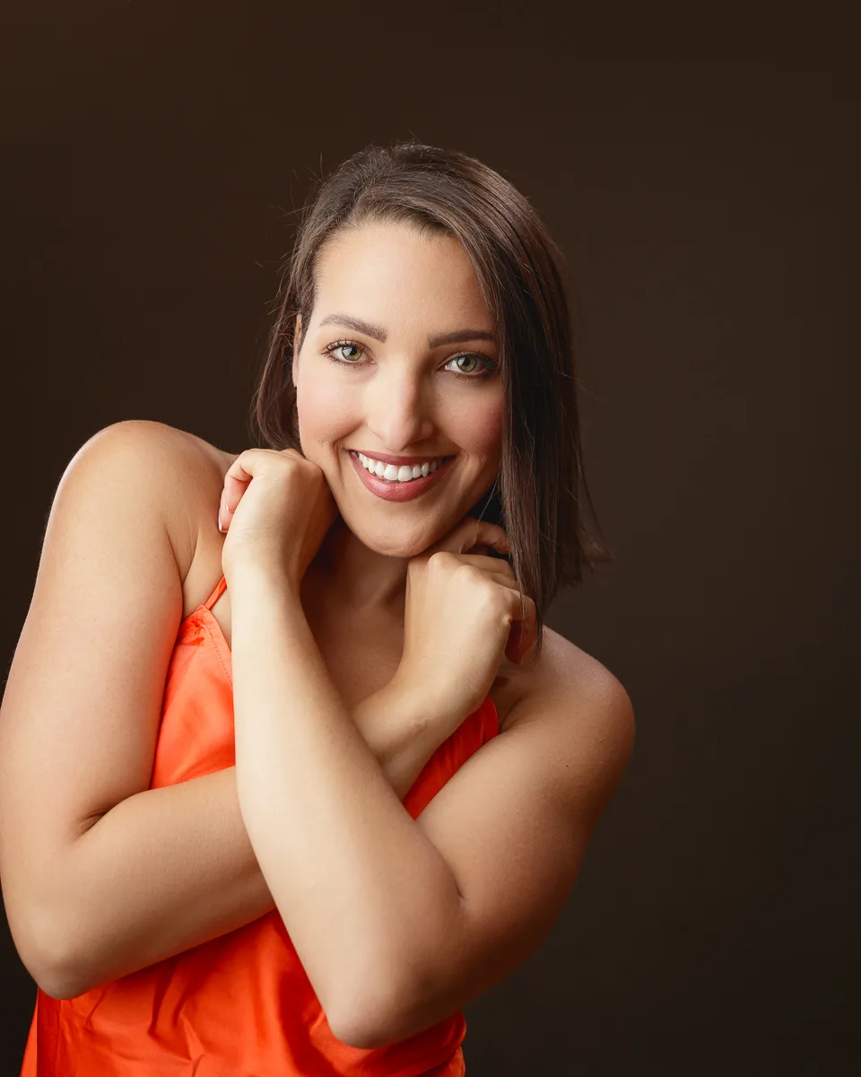 Woman in orange dress smiling warmly